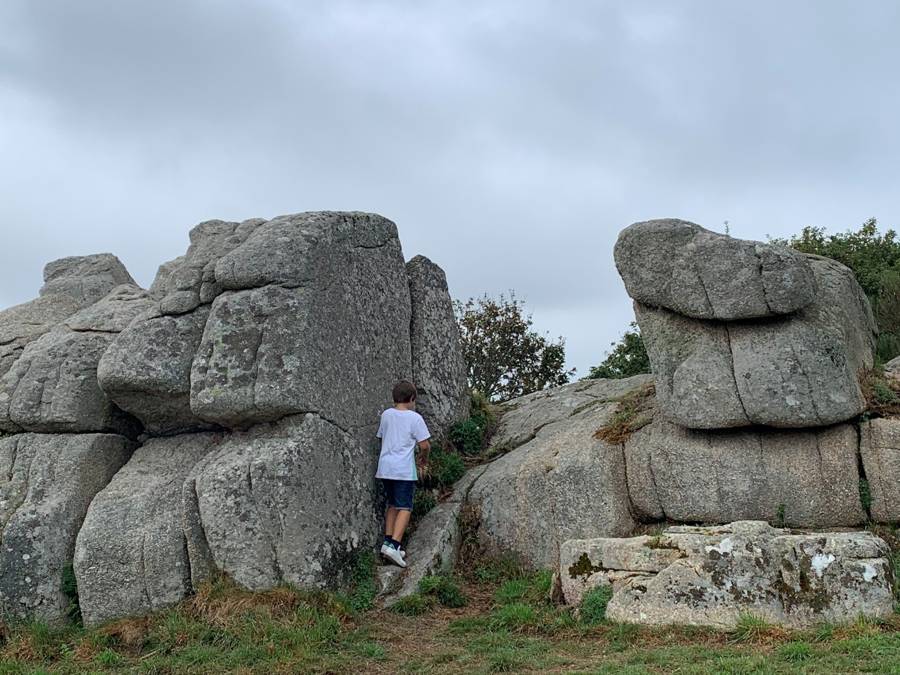 De grands rochers de granit ; un enfant grimpe entre eux.